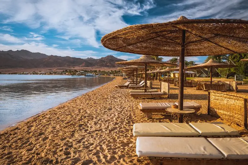 una Playa de Dahab en Egipto con sombrillas y tumbonas frente al Mar Rojo.