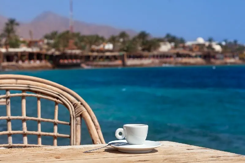 Taza de café sobre una mesa con vista al Mar Rojo en Dahab, Egipto.