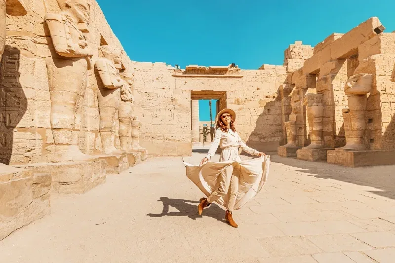 Viaggiatrice nel cortile di un tempio a Luxor con pilastri osiriaci