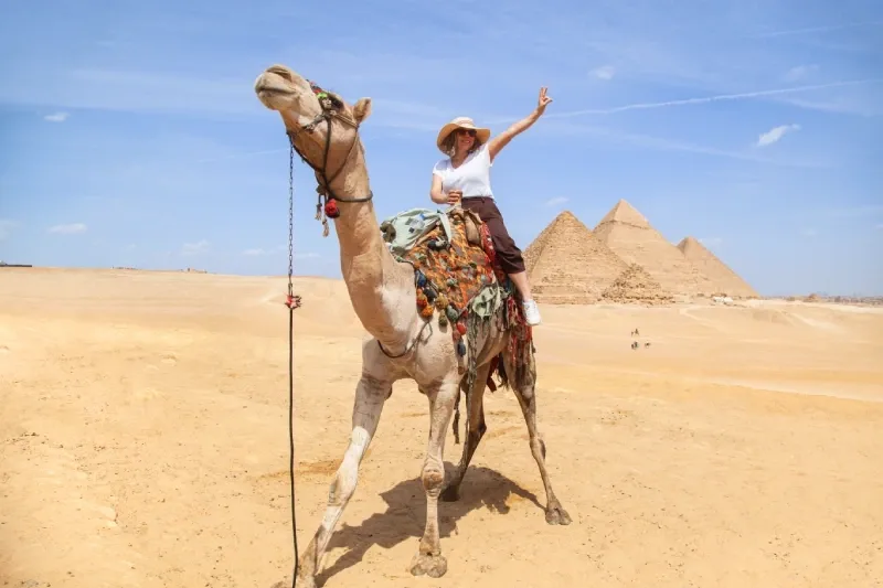 Turista a dorso di cammello davanti alle Piramidi di Giza
