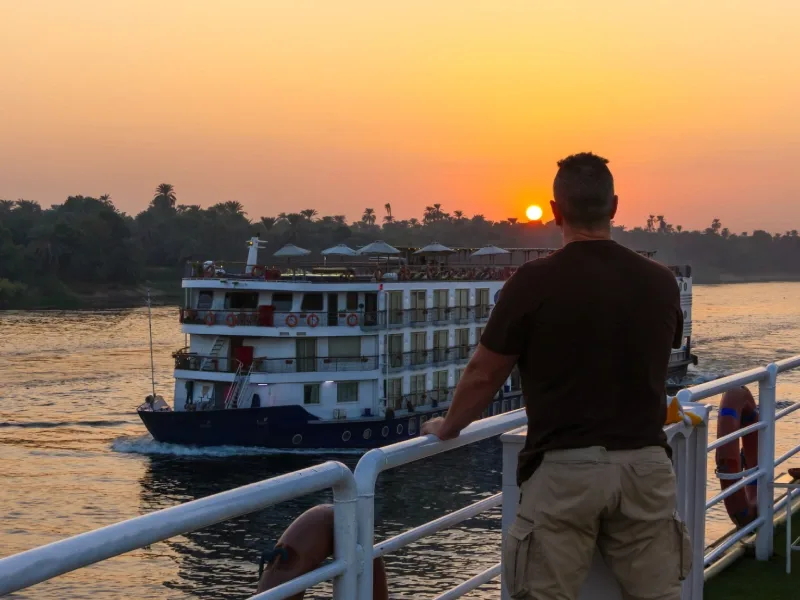 Viaggiatore osserva una motonave sul Nilo al tramonto durante una crociera