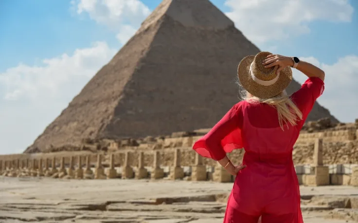 Come Sono State Costruite Le Piramidi, una donna indossa un vestito rosso davanti alle piramidi di Giza