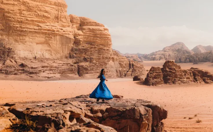 donna con un abito blu che ammira il suggestivo paesaggio del wadi rum, visto per la giordania