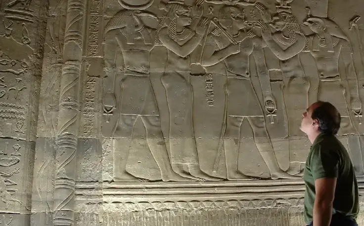 una turista ammira le opre d'arte dell'antico egitto, iside e osiride