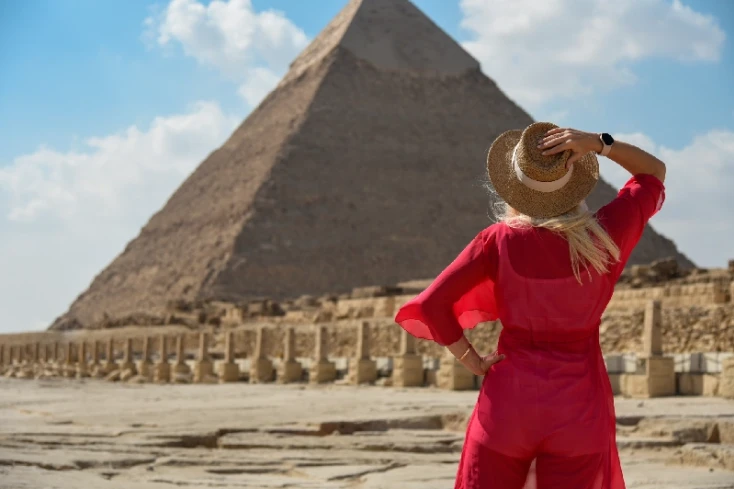 Clima in Egitto, una donna indossa un vestito rosso davanti alle piramidi