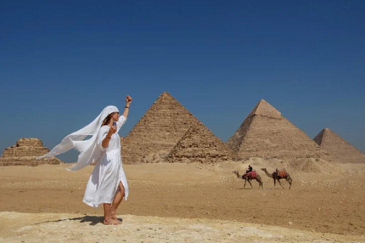 Clima in Egitto, una donna con un vestito bianco davanti alle piramidi