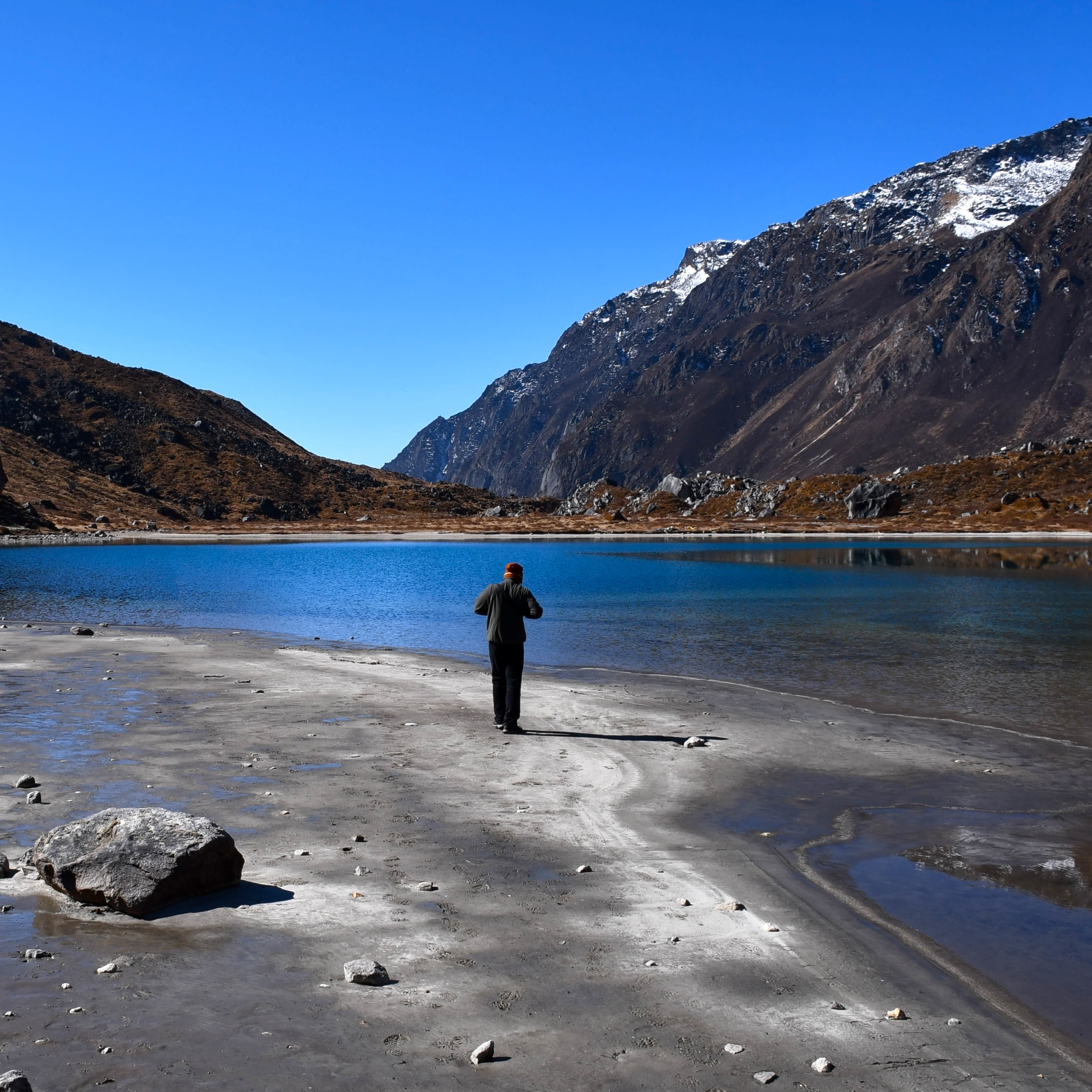 Guy walking beside a lake