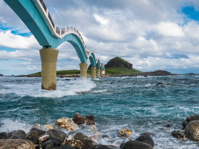 Walk on water at Taiwan's famous Sanxiantai Bridge - experience the thrill of crossing dramatic Pacific waves to reach this sacred offshore island.