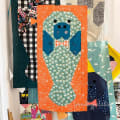 Woollypetals Manatee Migration Quilt showing one completed manatee block with blue body and green patterned tail on orange background