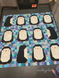 Woollypetals Penguin Social Quilt with black and white penguin blocks on patchwork background