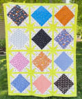 Woollypetals Sparked Quilt with colorful diamond blocks on bright lime sashing