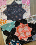 Woollypetals Floored10 quilt showing colorful fabric swatches arranged in a star pattern