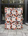 Woollypetals Ghost Party quilt displayed on patio with colorful patchwork squares