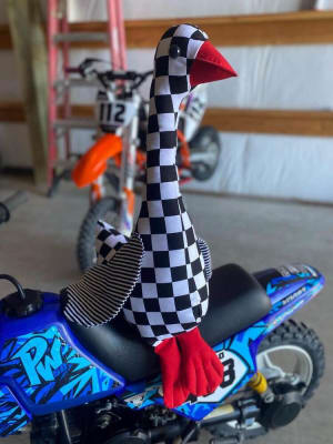 Woollypetals Silly Goose stuffed fabric goose with checkered pattern on blue toy vehicle