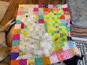 Woollypetals Squirrel quilt with colorful patchwork squares in progress on floor