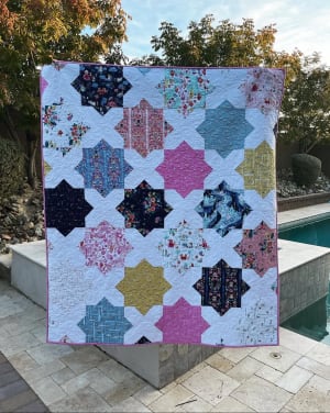 Woollypetals Floored10 quilt with colorful star blocks and white sashing