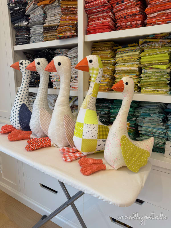 Woollypetals Silly Goose stuffed geese in various fabric patterns displayed on shelf
