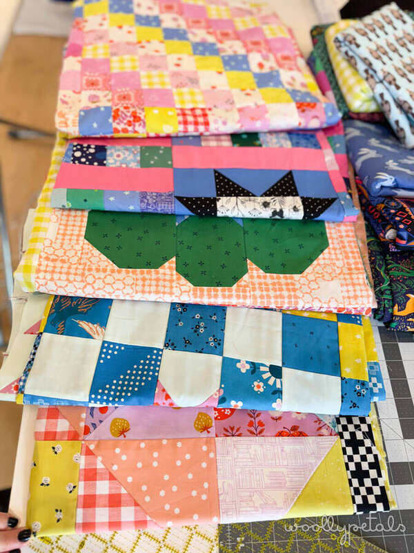 2 Week Quilt Top Challenge progress showing multiple colorful patchwork quilt tops stacked together