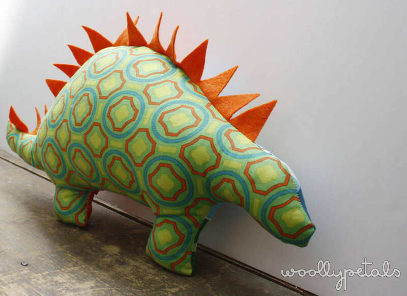 Colorful stuffed fabric dinosaur with green patterned body and orange spikes