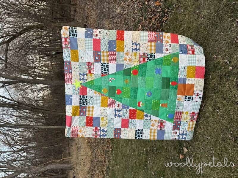 Patchwork quilt with colorful fabric squares and green Christmas tree appliqué