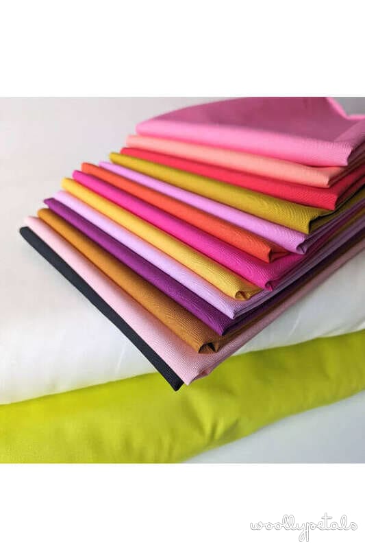 Colorful fabric bundles stacked in rainbow order for quilting