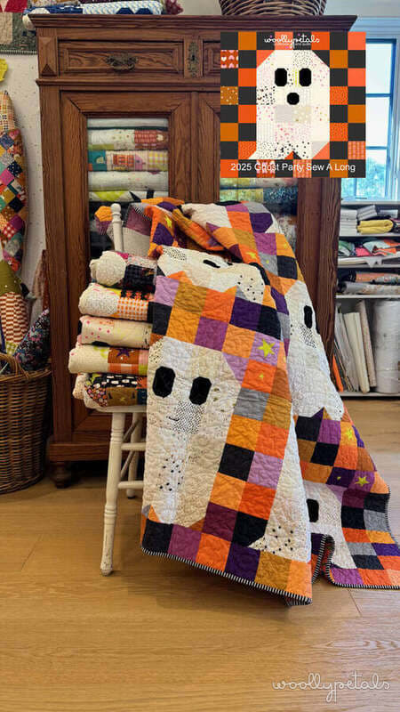 Woollypetals Ghost Party quilt draped over wooden chair with orange, purple, and cream fabrics
