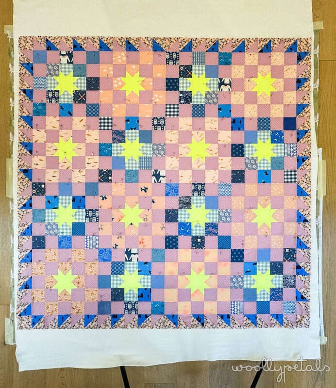 Woollypetals New Star Beginner Quilt with yellow stars and pieced backing on design wall