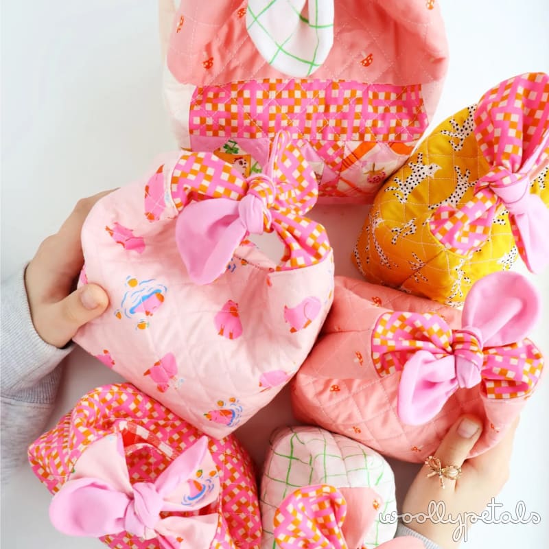 Colorful fabric stuffed animals with pink bows held in hands