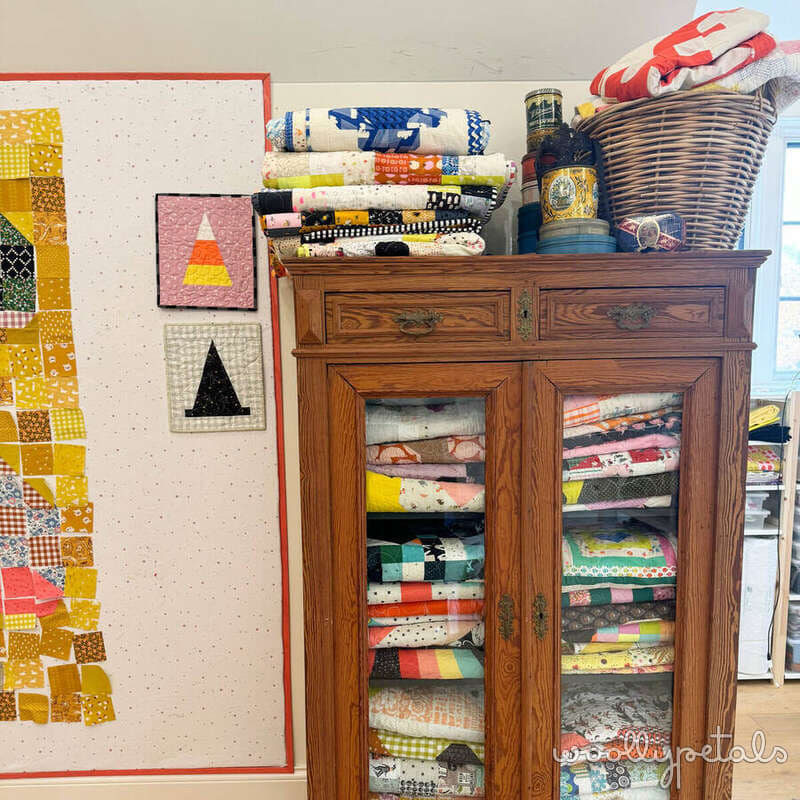 Sewing room storage with wooden cabinet displaying colorful fabric rolls and stacked quilting materials