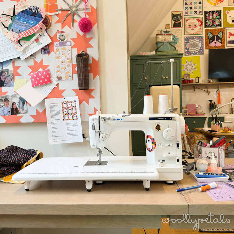 Sewing room workspace with white sewing machine and colorful design wall