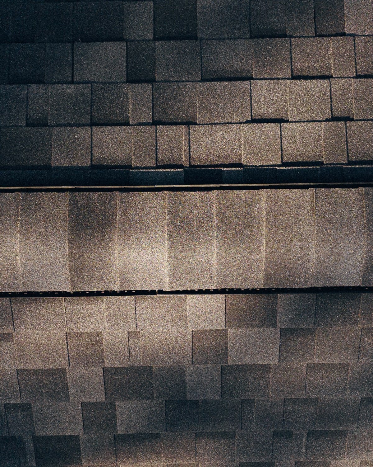 A close-up of new asphalt shingles along a roof ridge