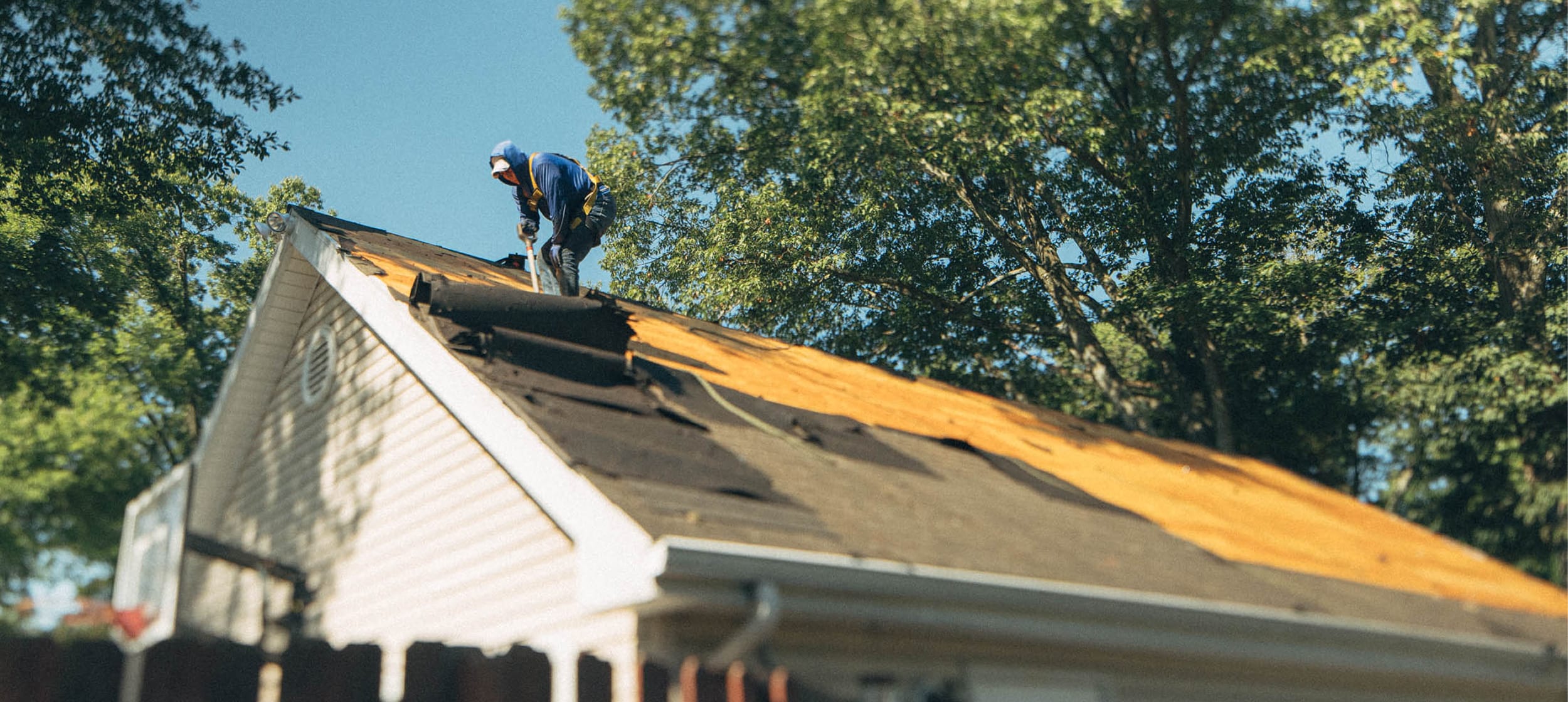 A roofer working on the gable of a home during a roof replacement