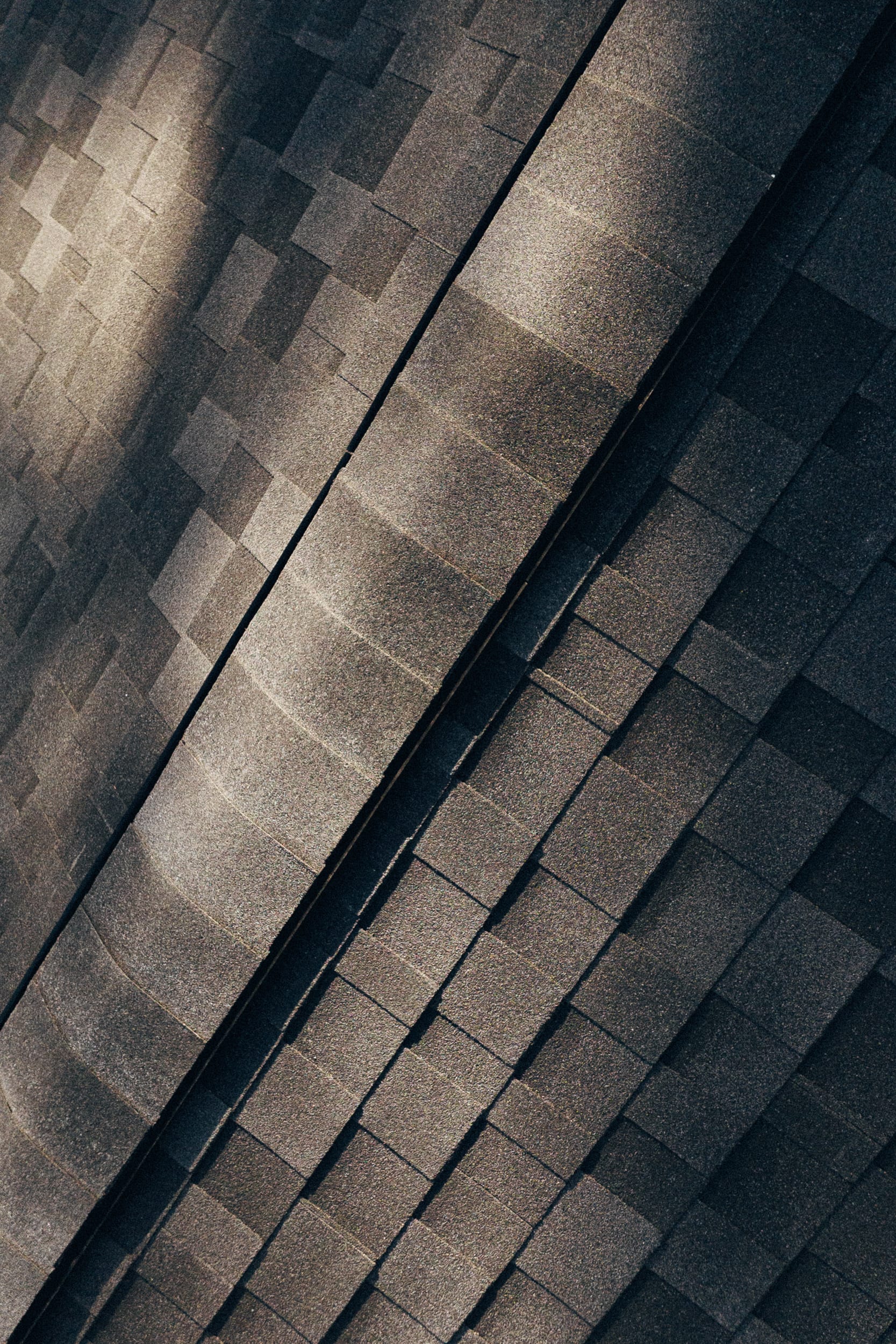 A close-up of new asphalt shingles along a roof ridge