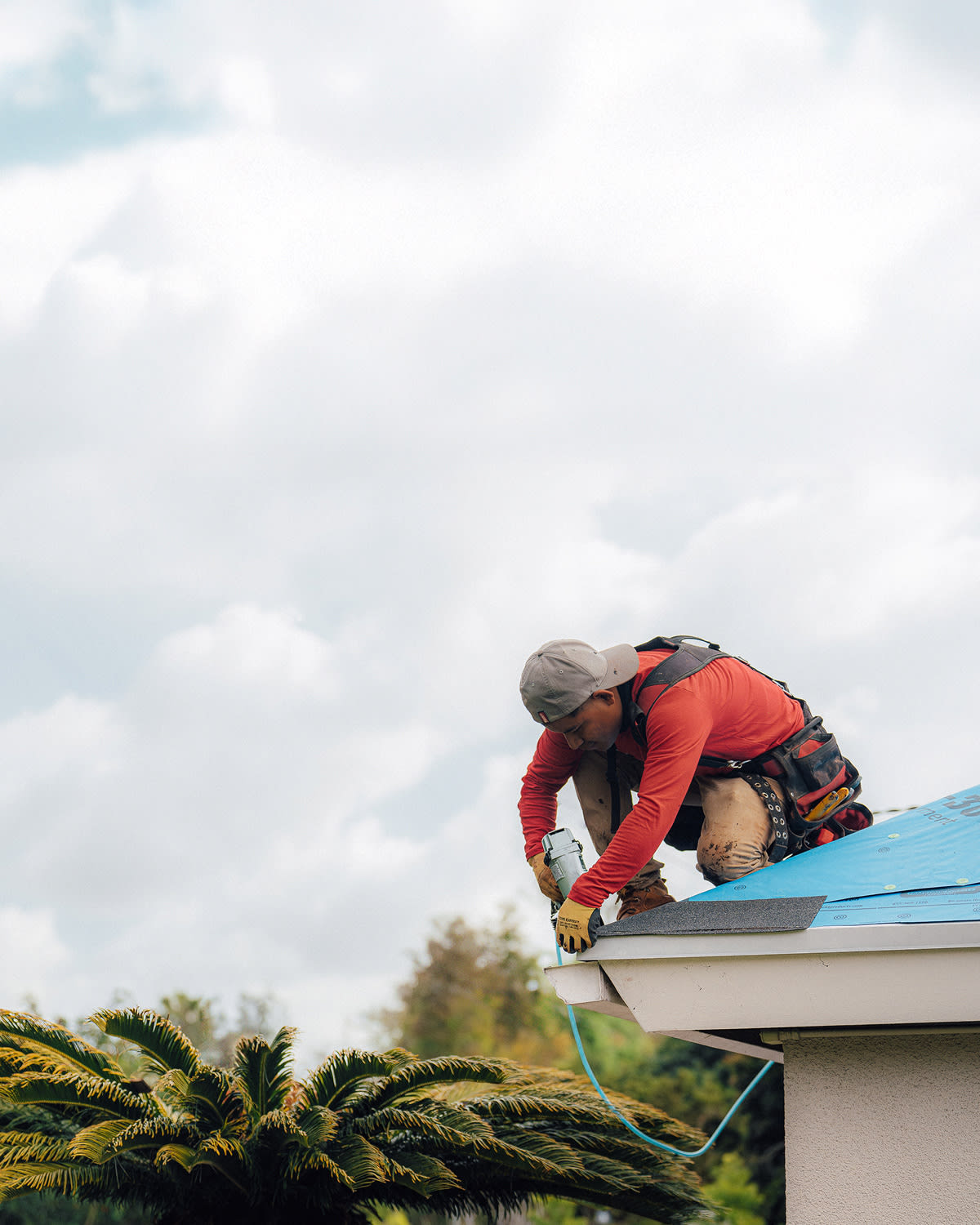 A roofer fastening underlayment along the edge of a roof