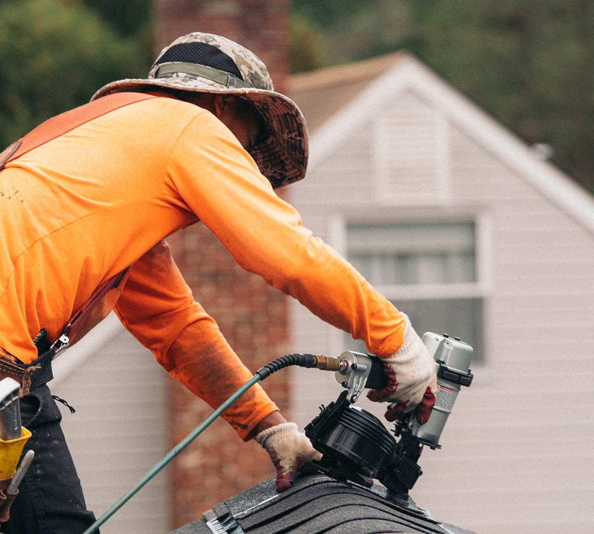 A Remi crew member nailing shingles along a ridge
