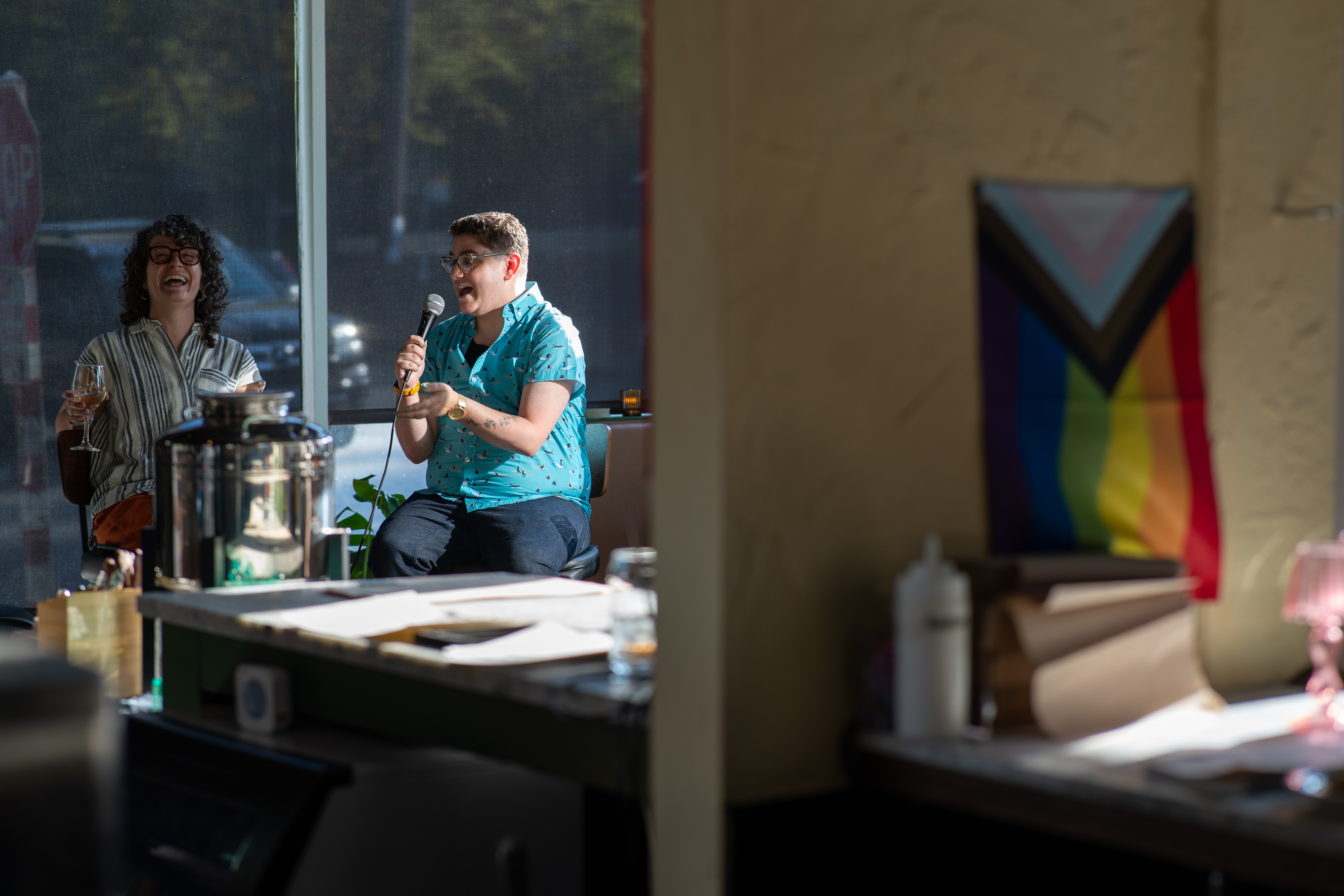 Maggie Mertens and Julie Kliegman sitting on bar stools, holding microphones and laughing about something.