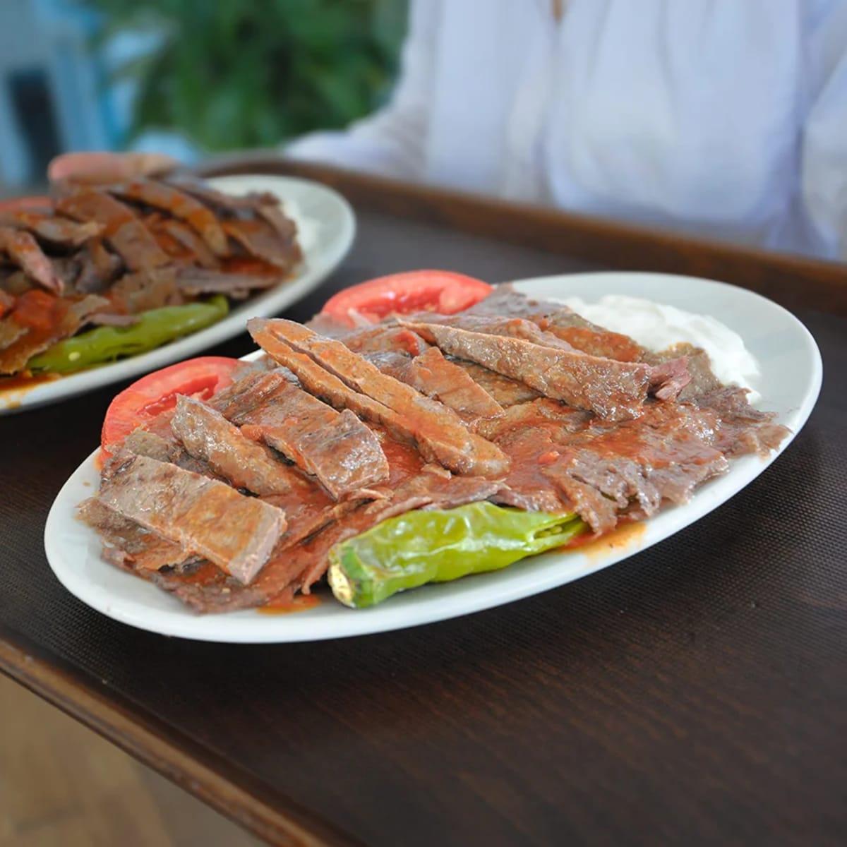 Ahşap masada servis edilen İskender kebap tabakları