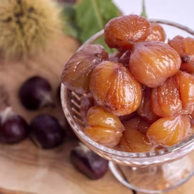 Bursa'nın meşhur Kestane Şekeri tatlısının cam kasede sunumu ve arka planda ham kestaneler.