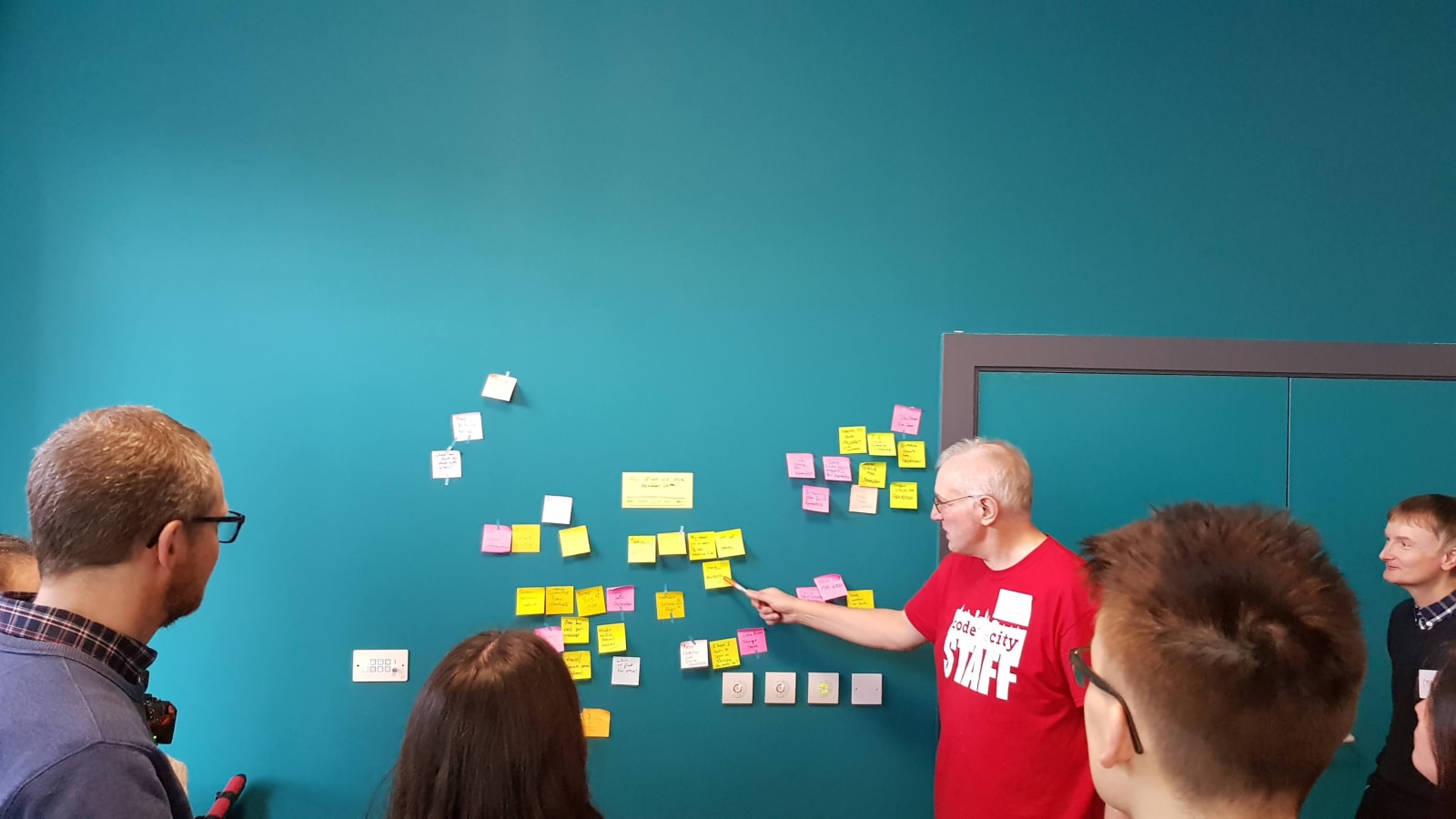 Personas frente a una pared con notas adhesivas durante un taller de trabajo