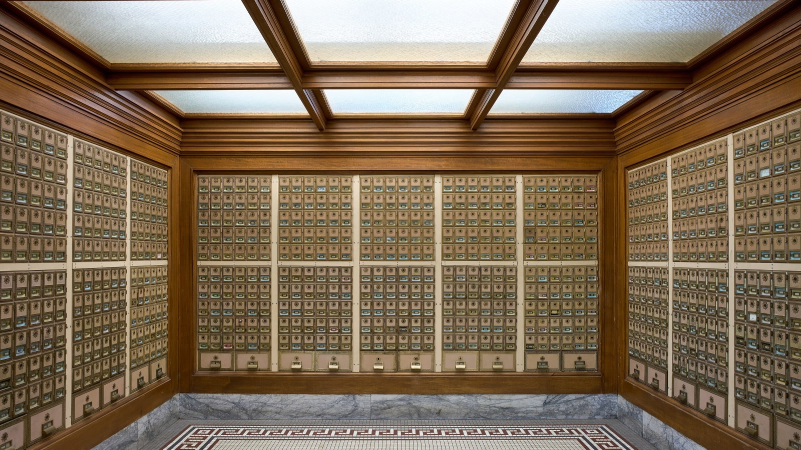 Sala de apartados postales antiguos con cientos de casilleros de latón cubriendo las paredes