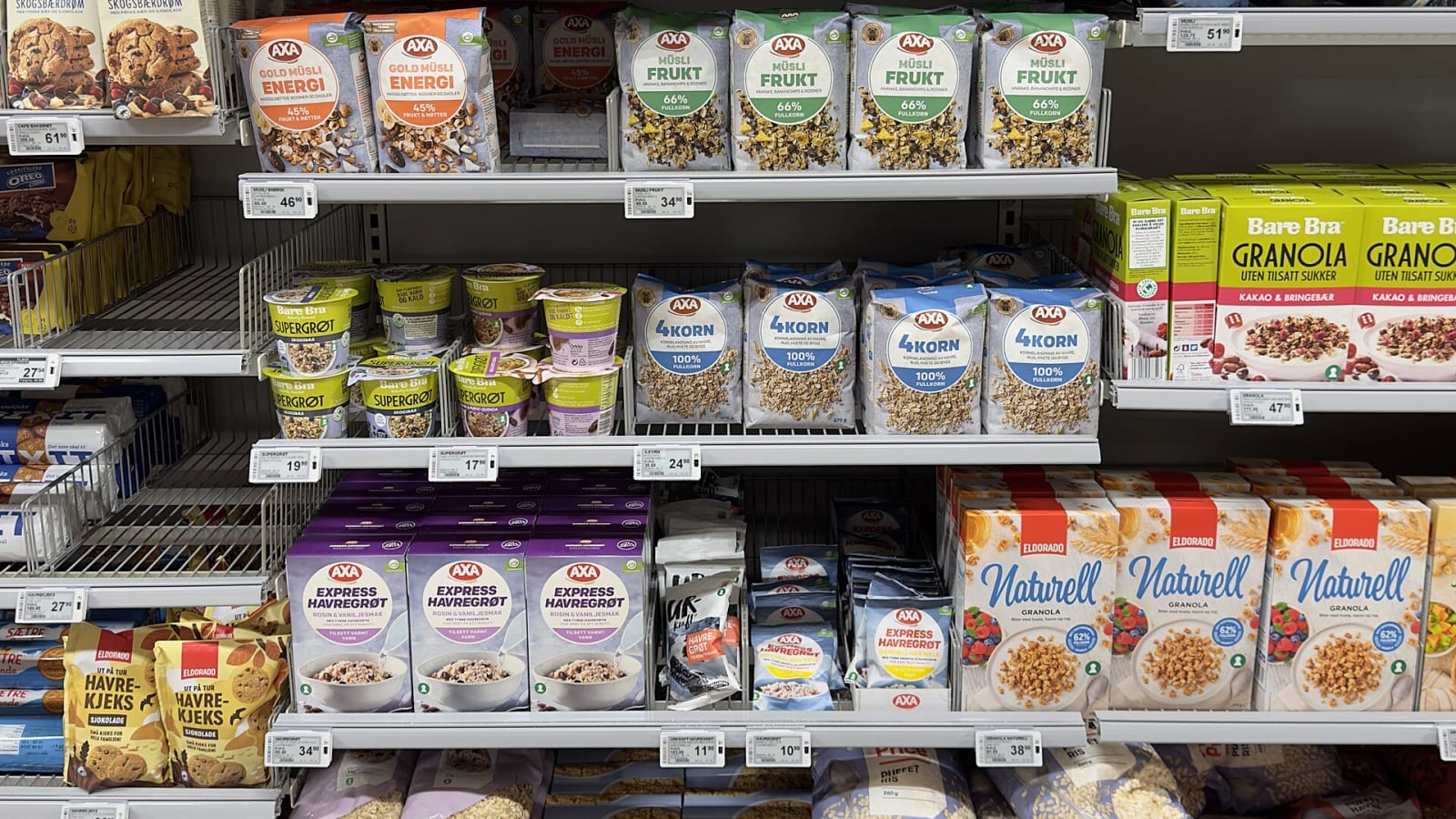 Lineal de supermercado con cajas y bolsas de cereales y etiquetas electrónicas de precio en los estantes