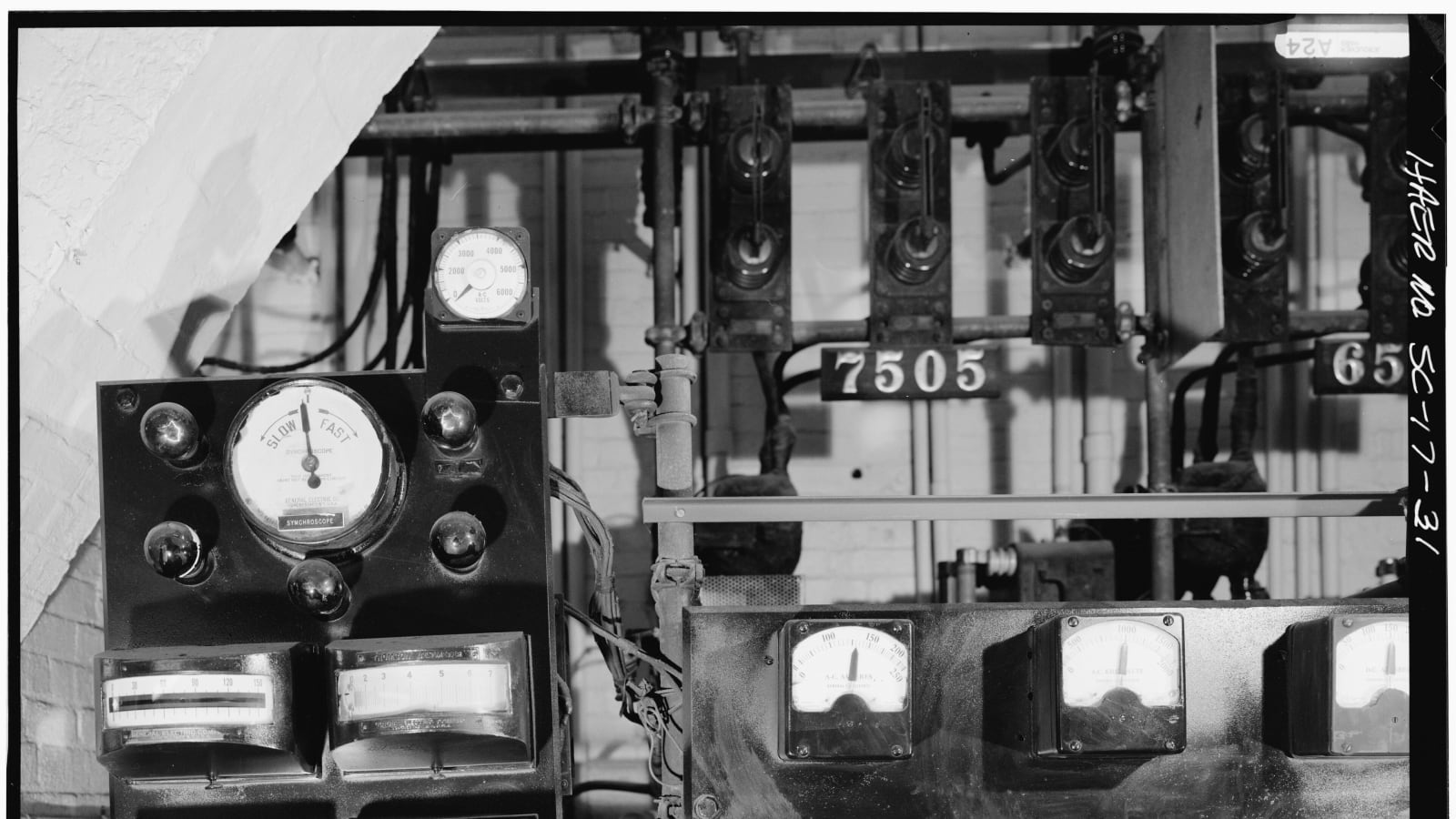 Panel de control industrial en blanco y negro con varios medidores de aguja, uno de ellos marcado «slow» y «fast»