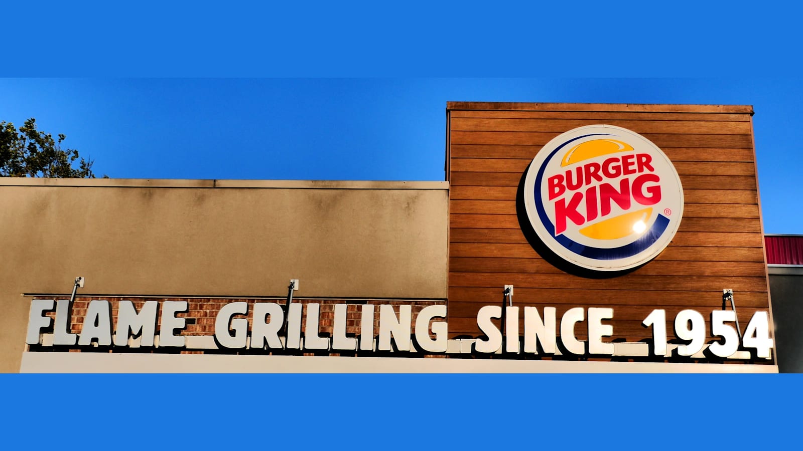 Fachada de un restaurante Burger King con el logotipo y el rótulo «Flame grilling since 1954» en letras blancas