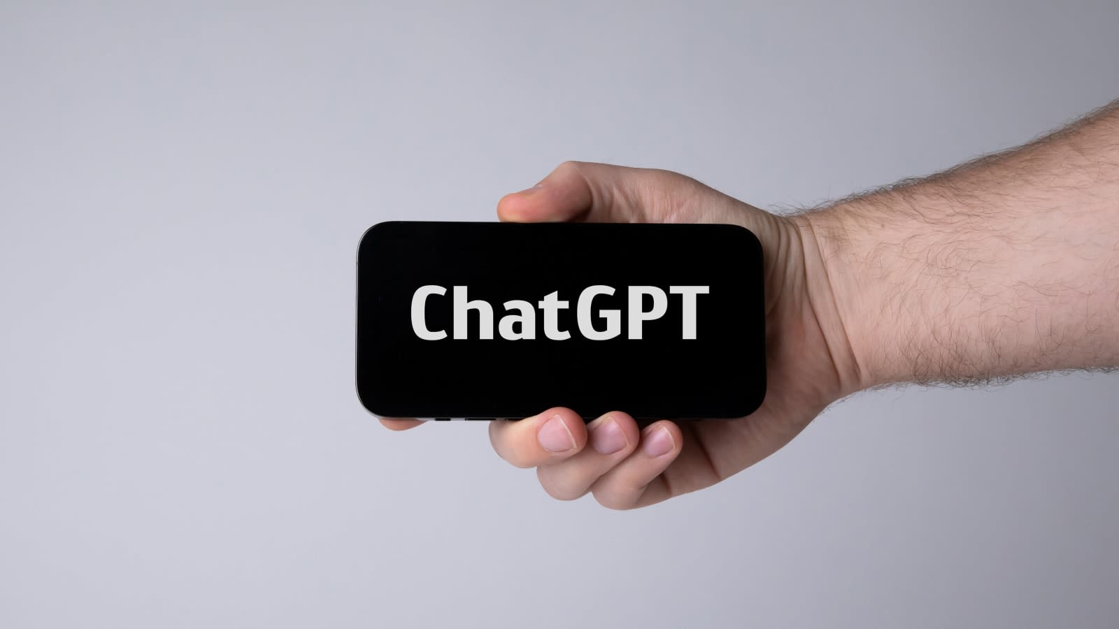Una mano sostiene un teléfono móvil con la palabra ChatGPT en la pantalla