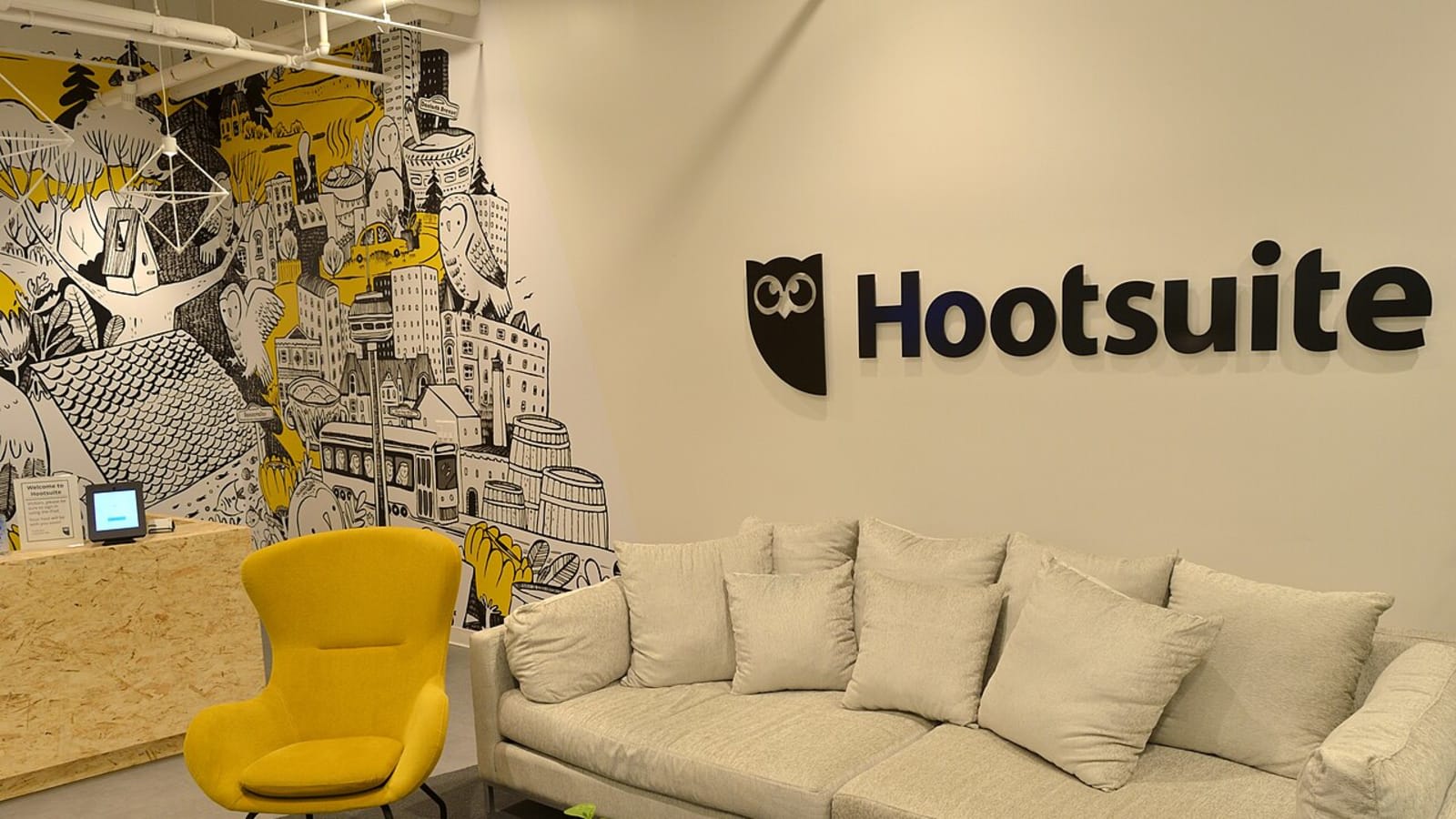 Recepción de la oficina de Hootsuite en Toronto, con el logotipo del búho en la pared y un sofá
