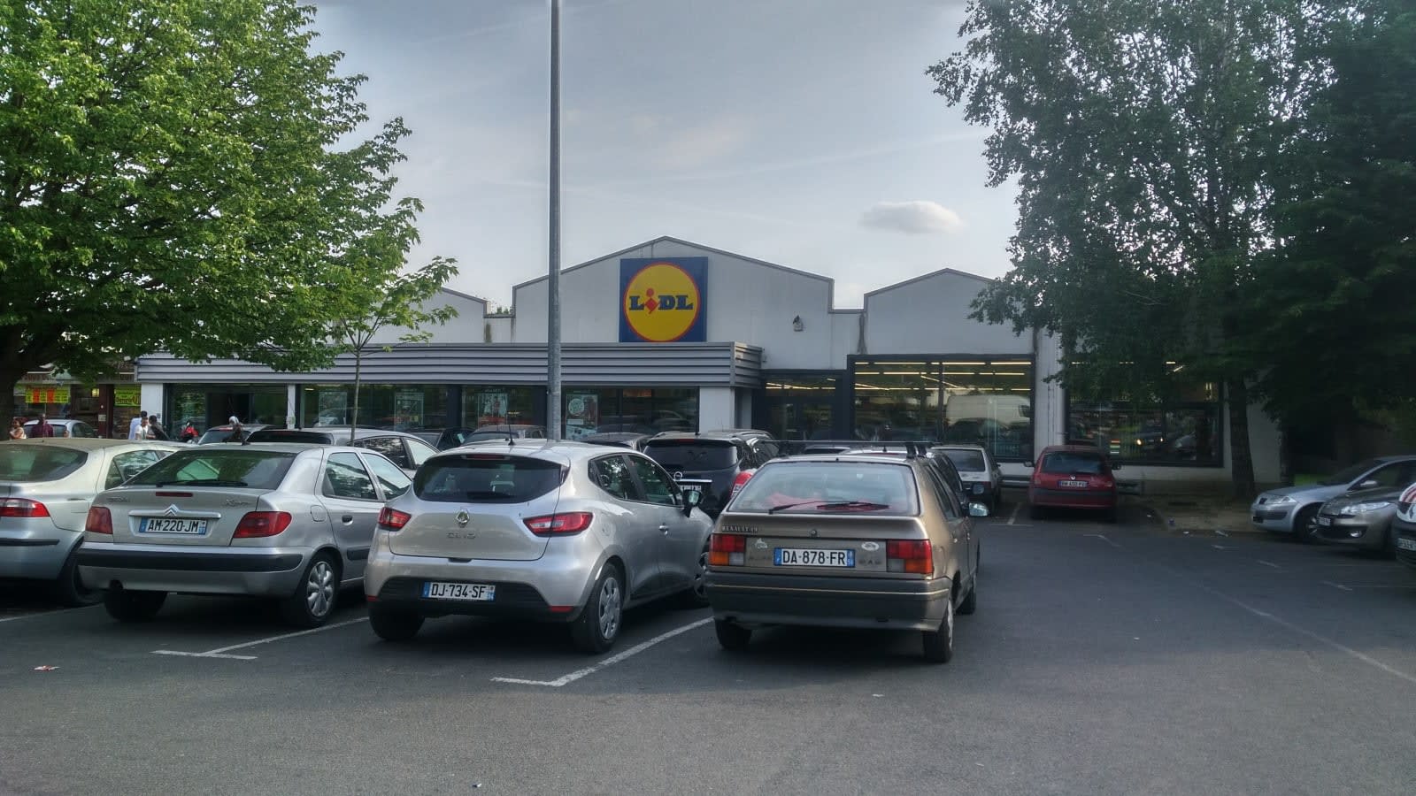 Exterior de un supermercado Lidl con su logotipo sobre la fachada y coches aparcados delante