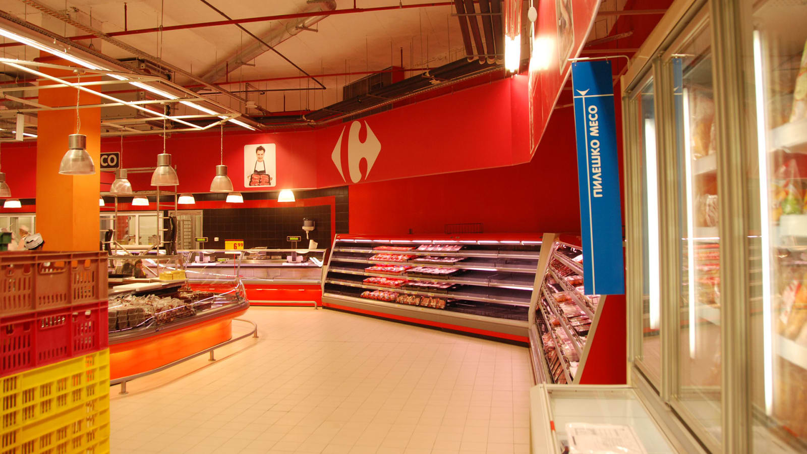 Interior de un supermercado Carrefour con el logotipo de la cadena en la pared y los mostradores de frescos