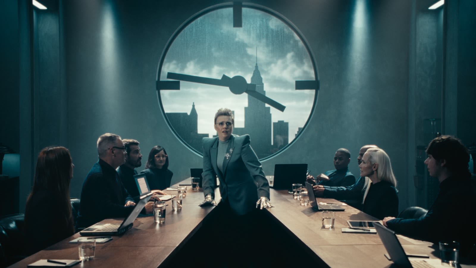 Kate McKinnon como CEO villana, de pie en una sala de juntas con su equipo, en el anuncio «Zoom Got It Done»