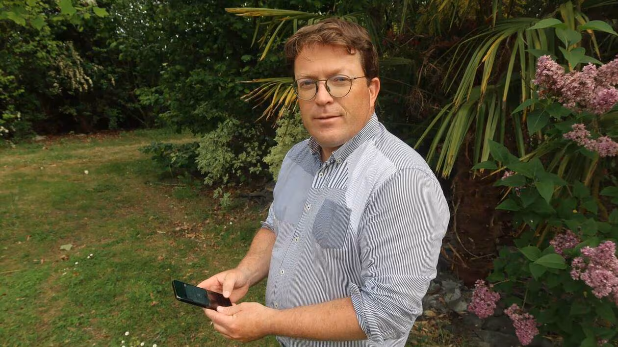 Damien Cariou tient un smartphone avec l'application SynApps en main
