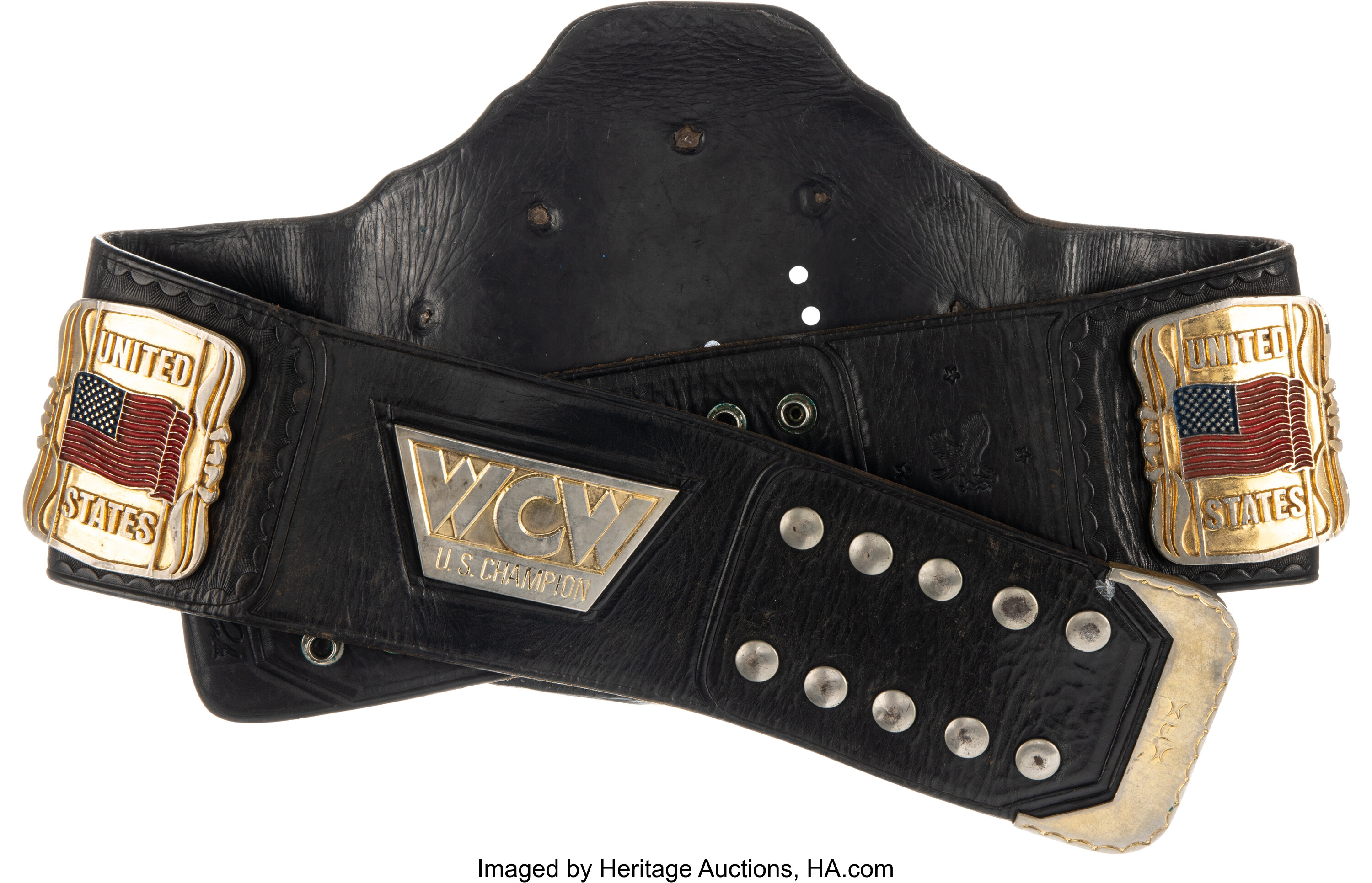 Angled full-length view of the 1990s WCW US Heavyweight Title highlighting distressed black leather strap, side plates and ring-used wear from event appearances